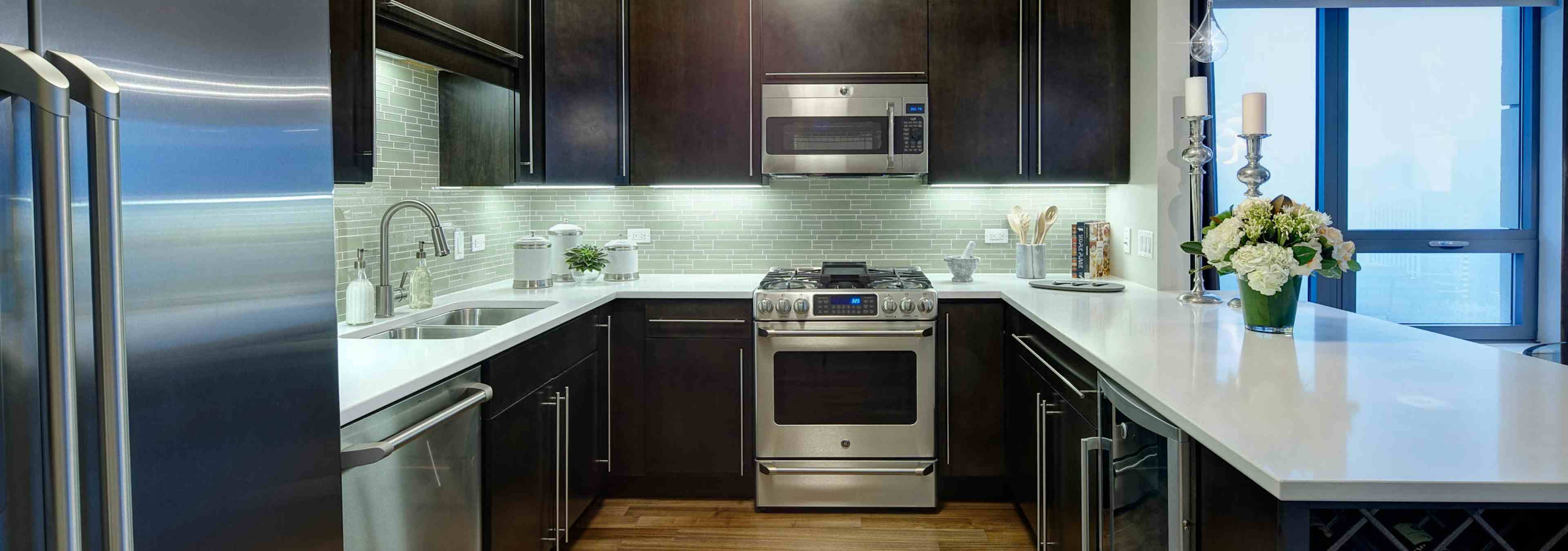 Interior view of an AMLI River North penthouse kitchen next to a floor to ceiling window overlooking the city buildings