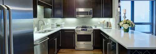 Interior view of an AMLI River North penthouse kitchen next to a floor to ceiling window overlooking the city buildings