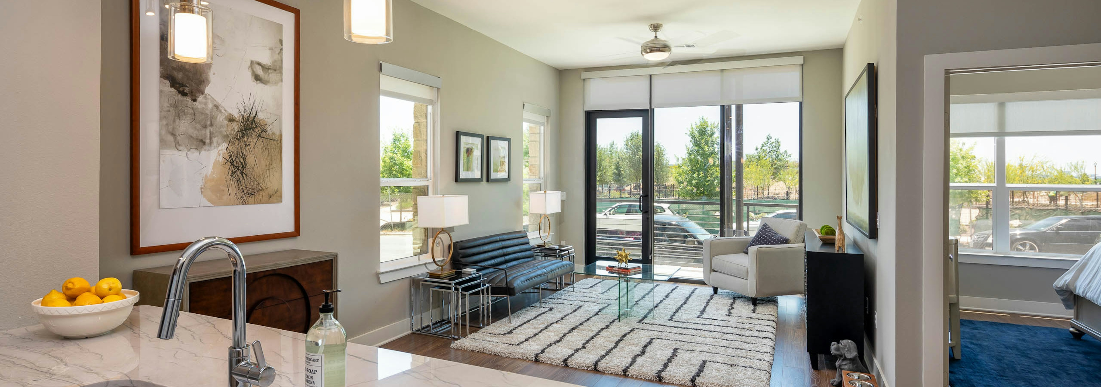 Living room at AMLI on Aldrich with light walls and dark wood flooring with floor to ceiling windows showing daytime view