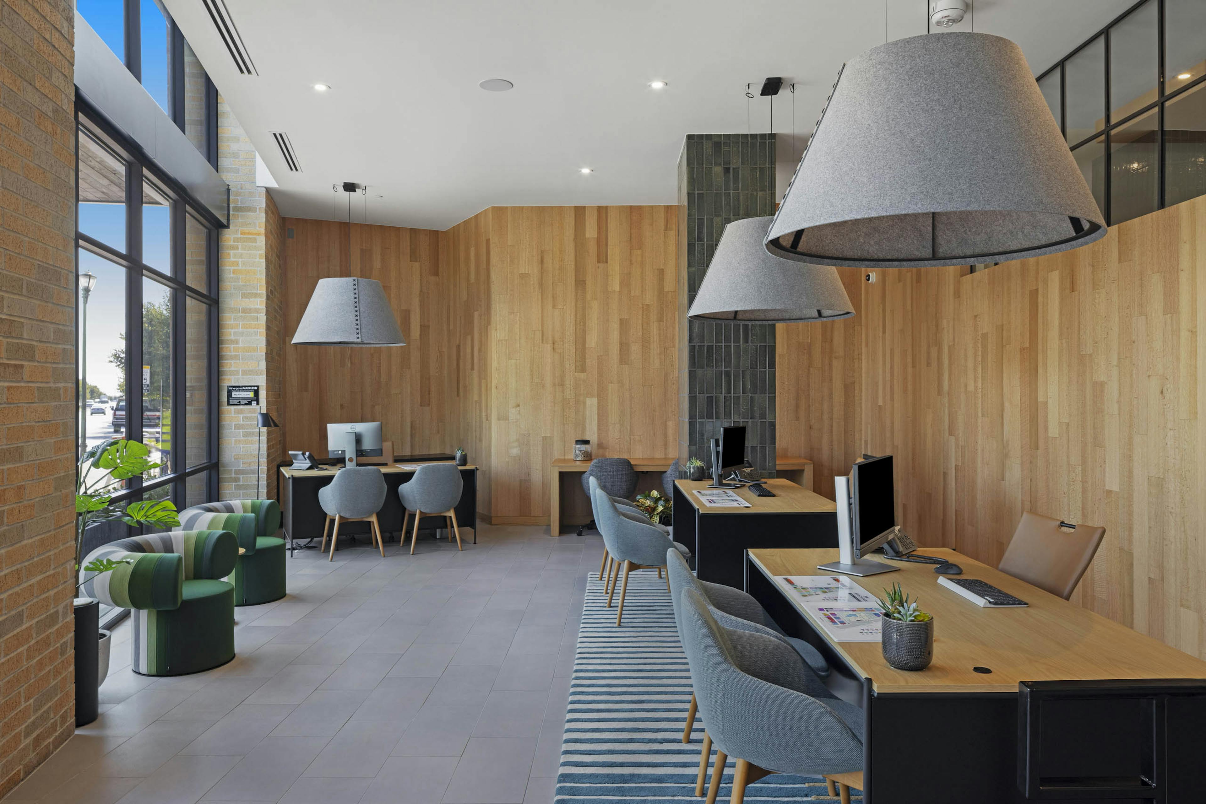 Leasing office at AMLI Branch Park with wood plank walls and desks with grey chairs and hanging light fixtures with grey shades
