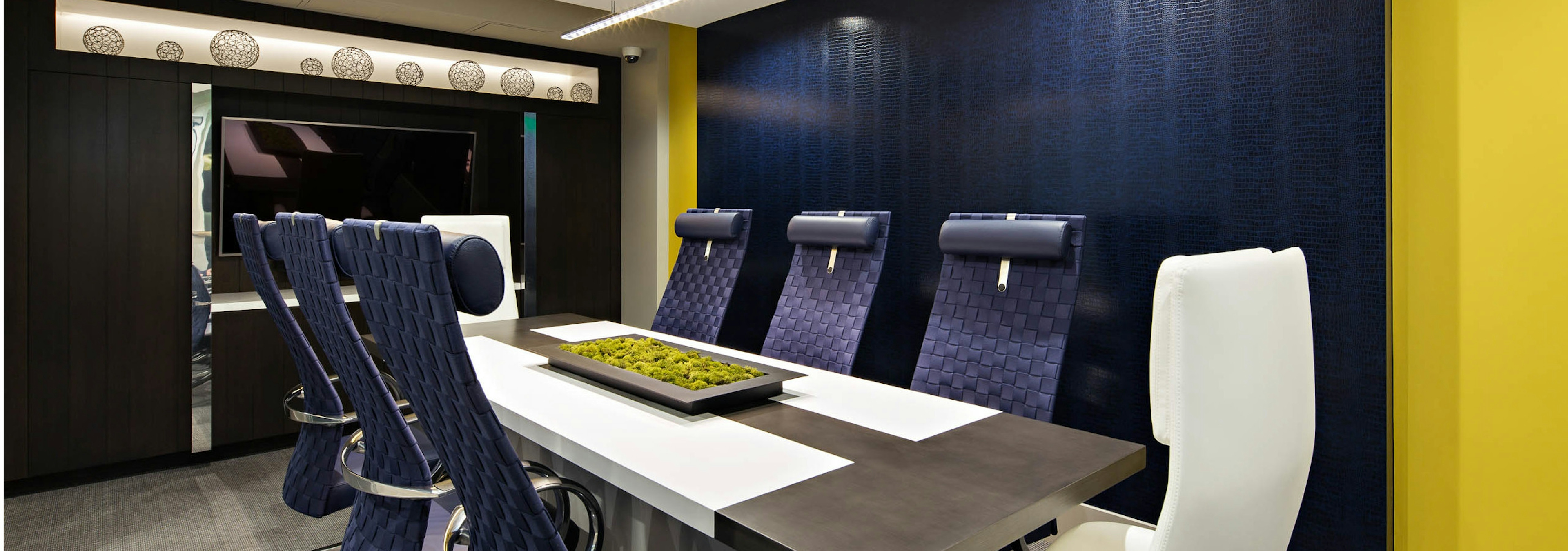 Interior view of the business center conference table at AMLI Lex on Orange apartments with big blue chairs and big screen TV