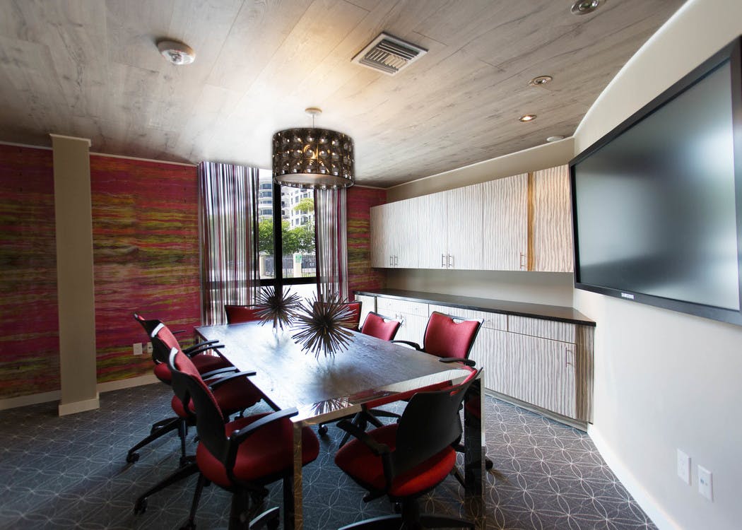 Interior conference room space at AMLI Dadeland with rectangular conference table and chairs, mounted tv and modern decor