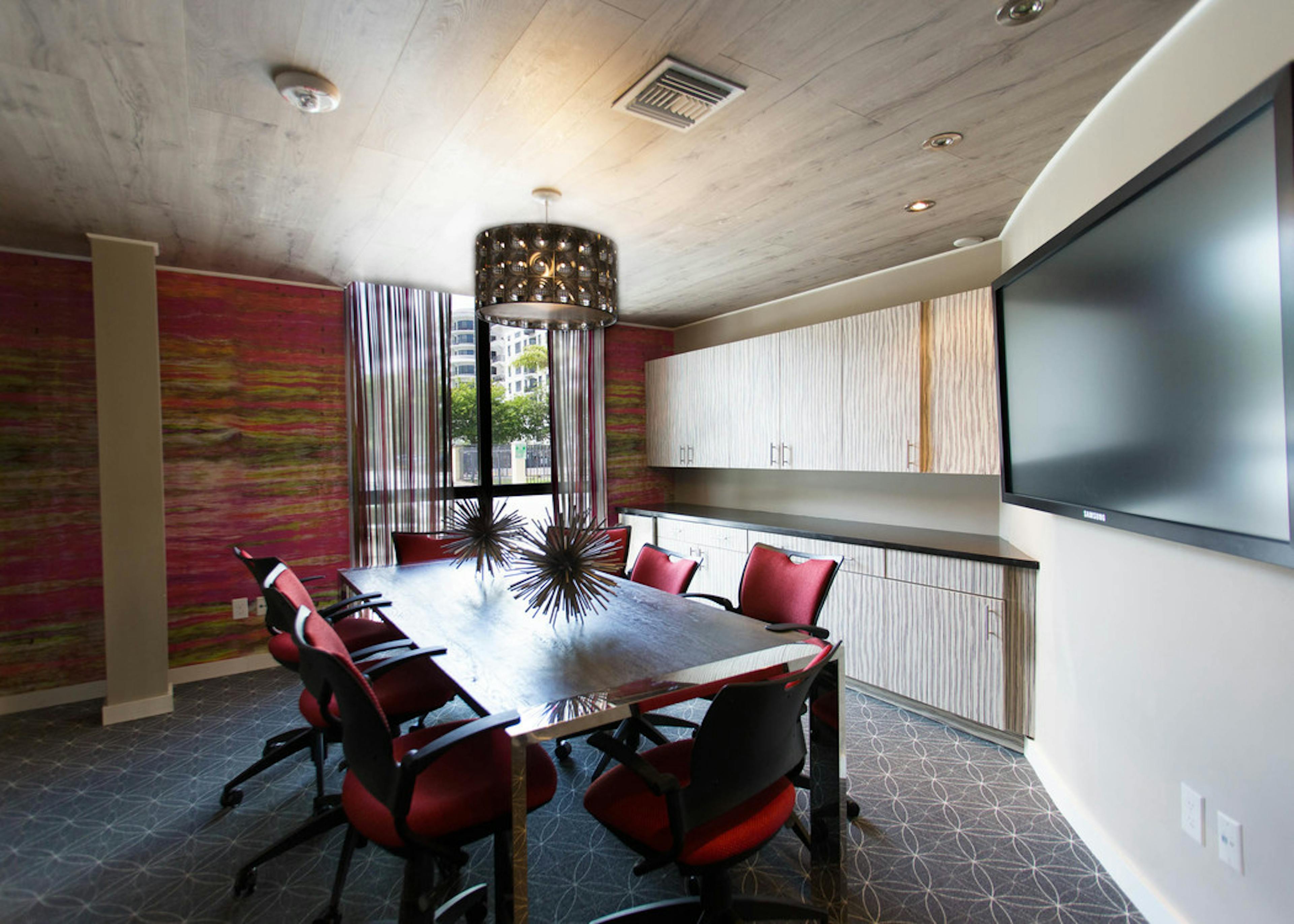 Interior conference room space at AMLI Dadeland with rectangular conference table and chairs, mounted tv and modern decor