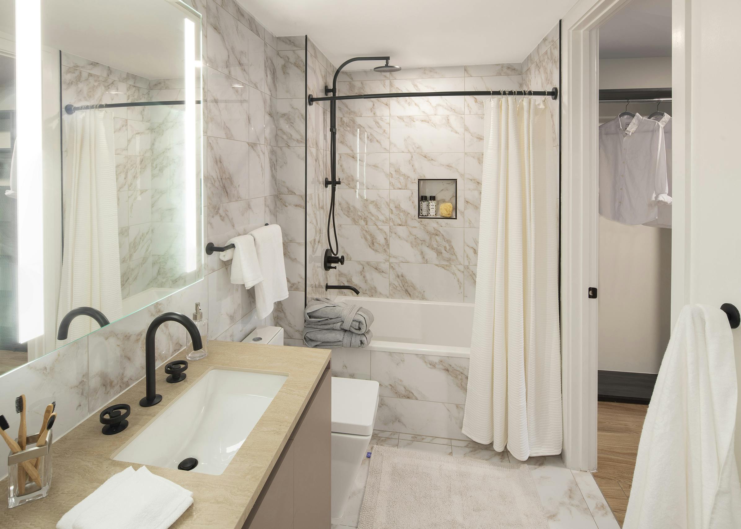 AMLI Midtown Miami apartment bathroom with marble floors and soaking tub with marble surround and vanity with backlit mirror