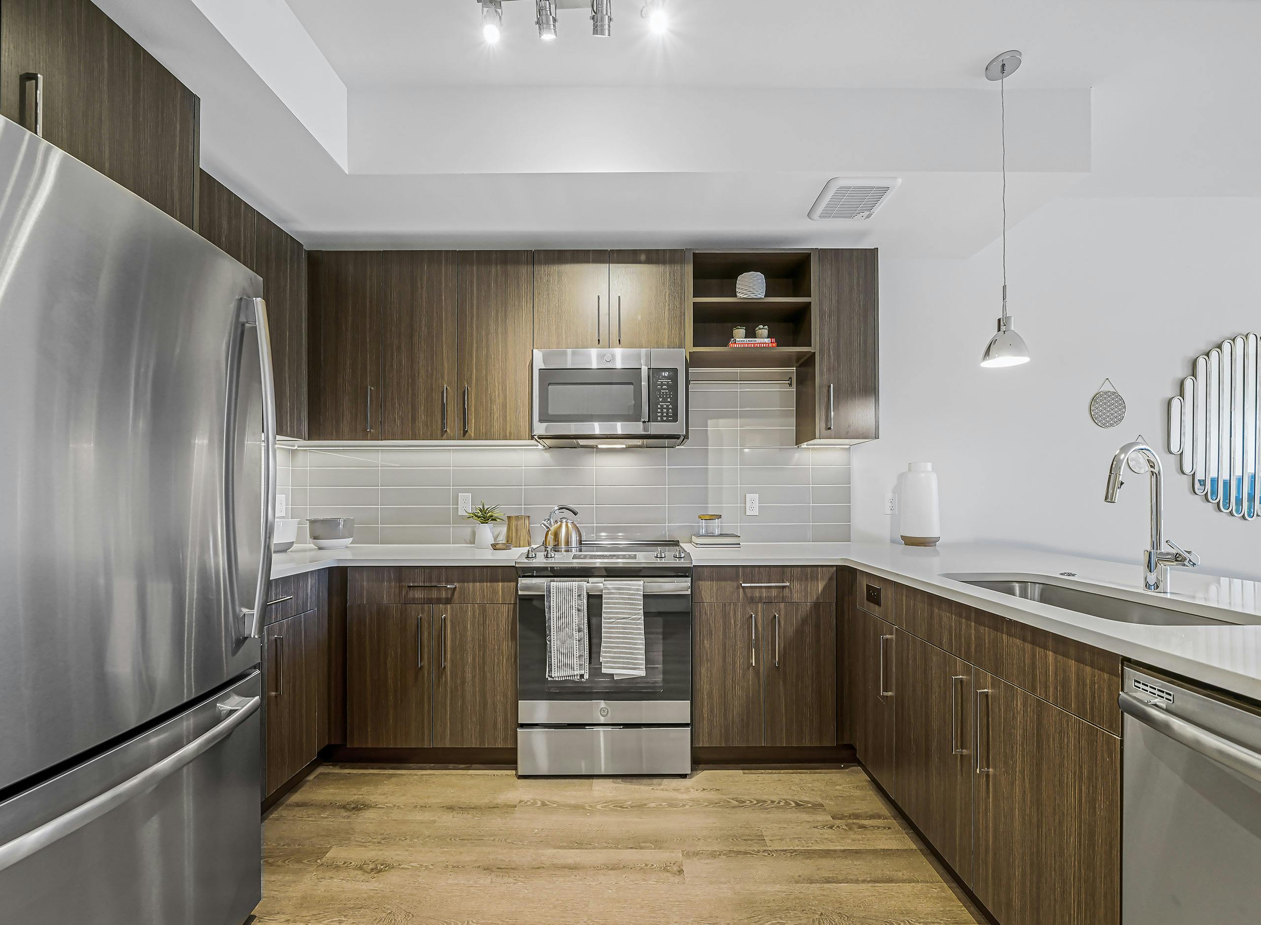 Interior of AMLI Spring District apartment kitchen with stainless steel appliances and brown wood style flooring