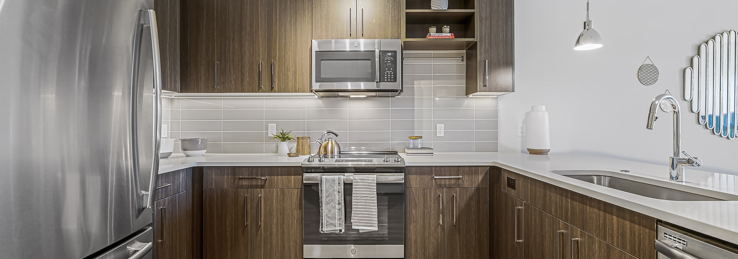 Interior of AMLI Spring District apartment kitchen with stainless steel appliances and brown wood style flooring
