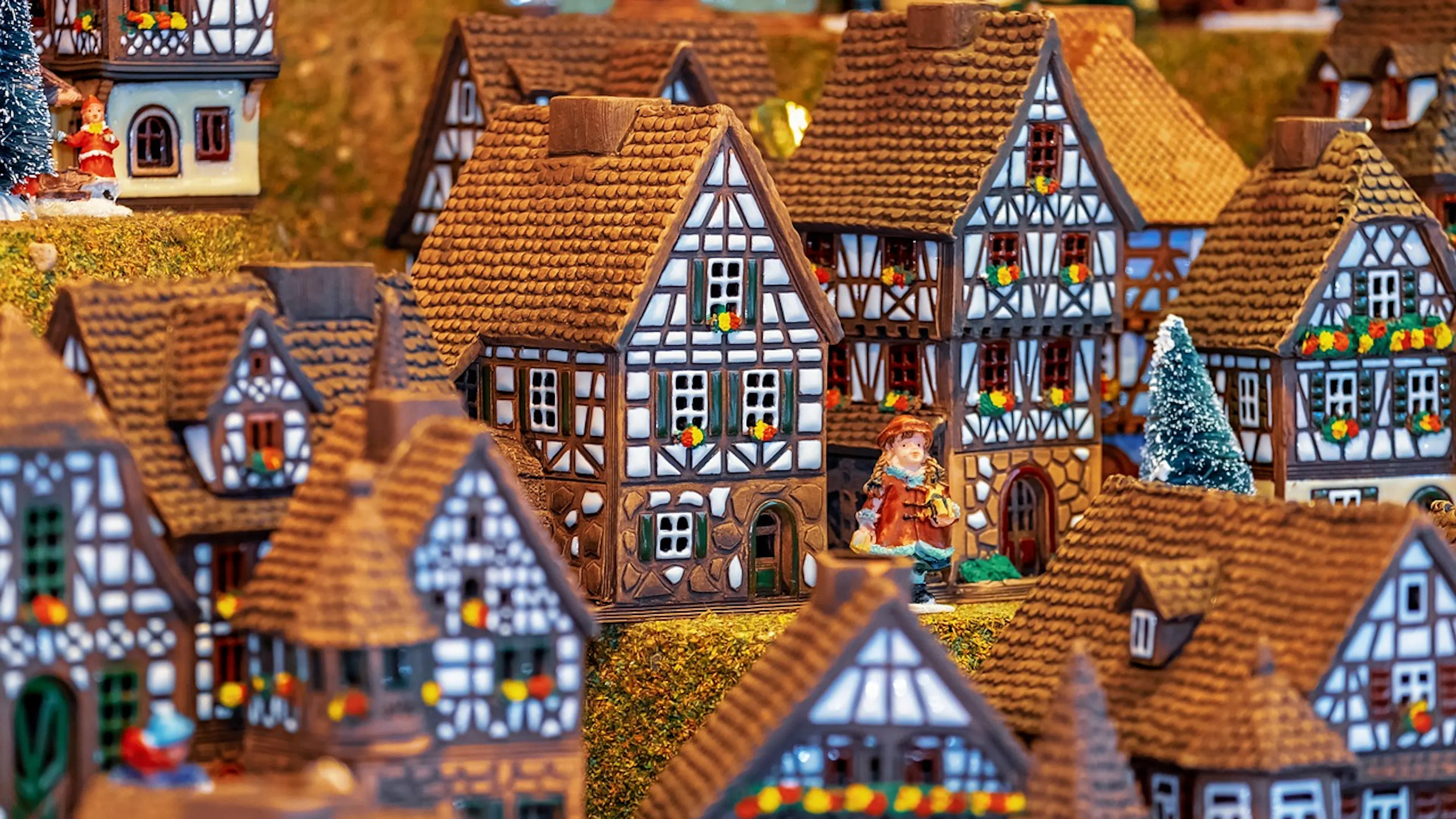 A close up of a model Bavarian town with a small figurine standing outside a model house