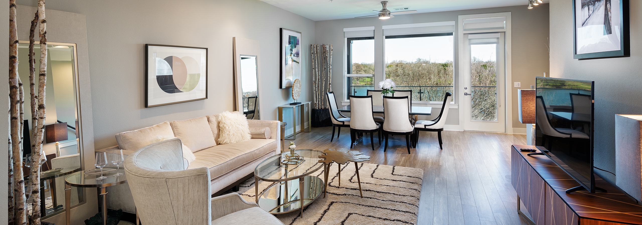 AMLI South Shore living room with light walls and floor to ceiling windows and a door leading to balcony with scenic view