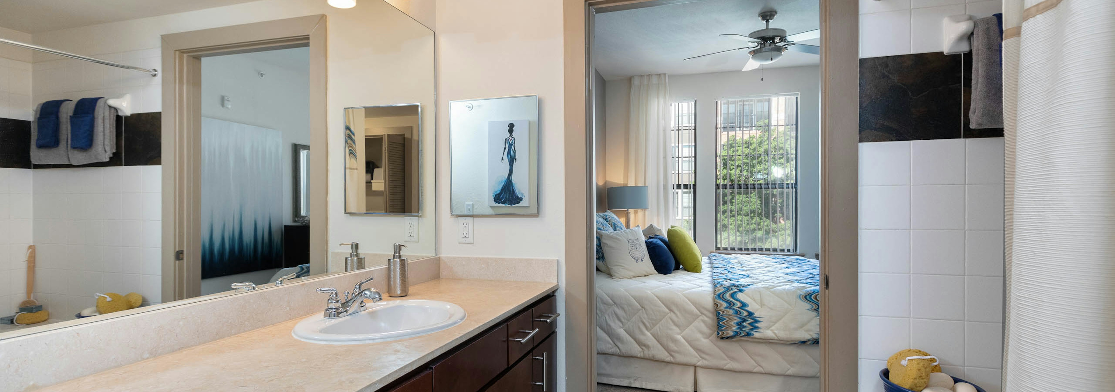 Bathroom at AMLI Eastside with a shower tub and vanity sink with light countertops and a peek into connecting bedroom