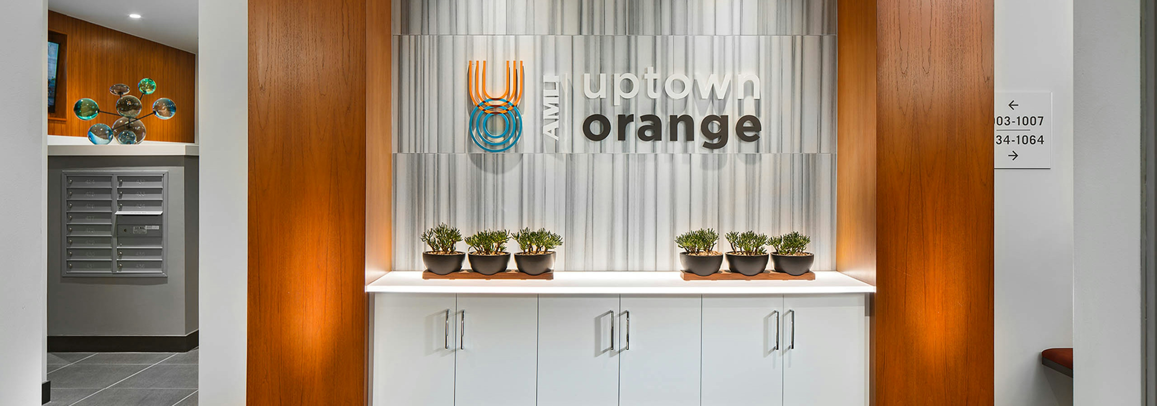 Interior of AMLI Uptown Orange apartment building entrance and monument sign on wall and six decorative succulent plants