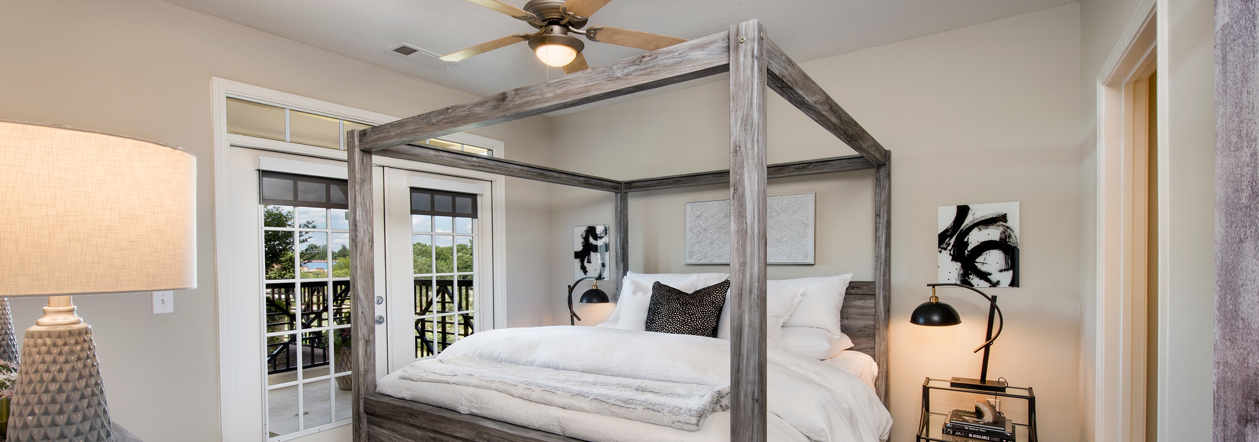 Bedroom at AMLI North Point with french doors leading outside and rustic styled decor with a canopy framed bed