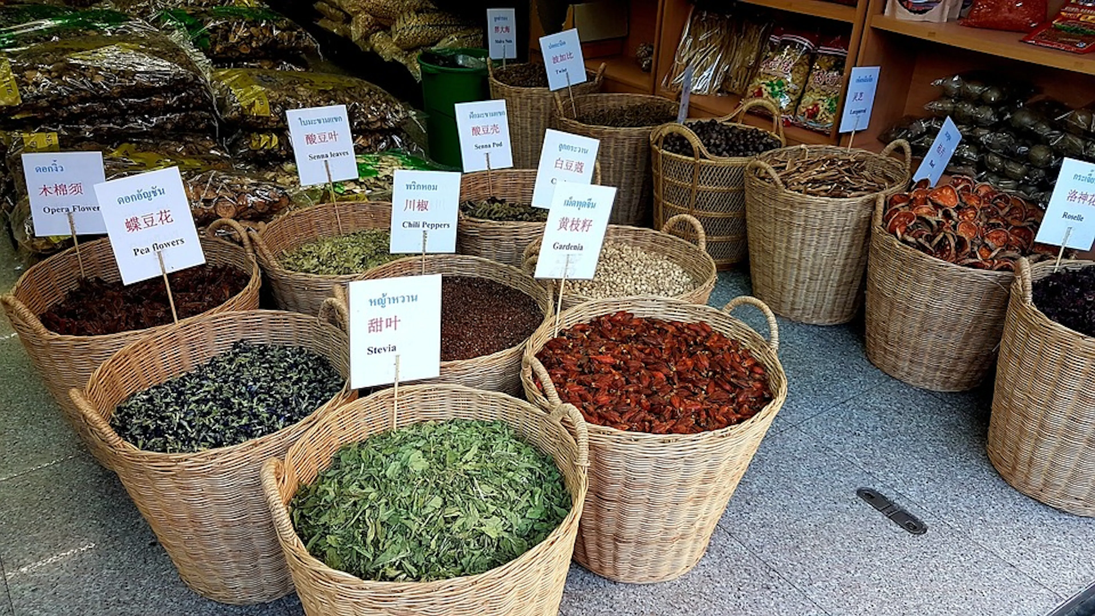 Rattan baskets full of spices and herbs arranged on a market floor