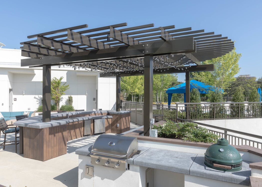 AMLI 3464 rooftop with barstool seating and blue cushion wicker couch with trees and white building facade in the background