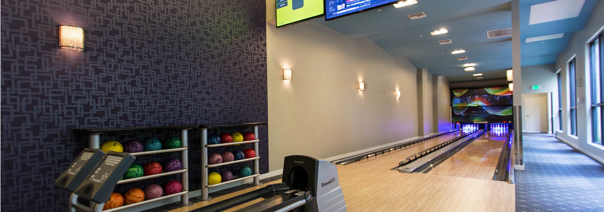 Interior of the two lane bowling alley at AMLI Dadeland apartment’s equipped with colorful bowling balls and tv screen