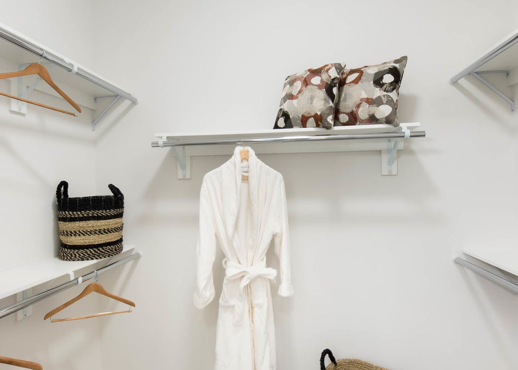Interior view of a walk in closet at AMLI Buckhead with wooden hangers and white shelving with beige colored walls