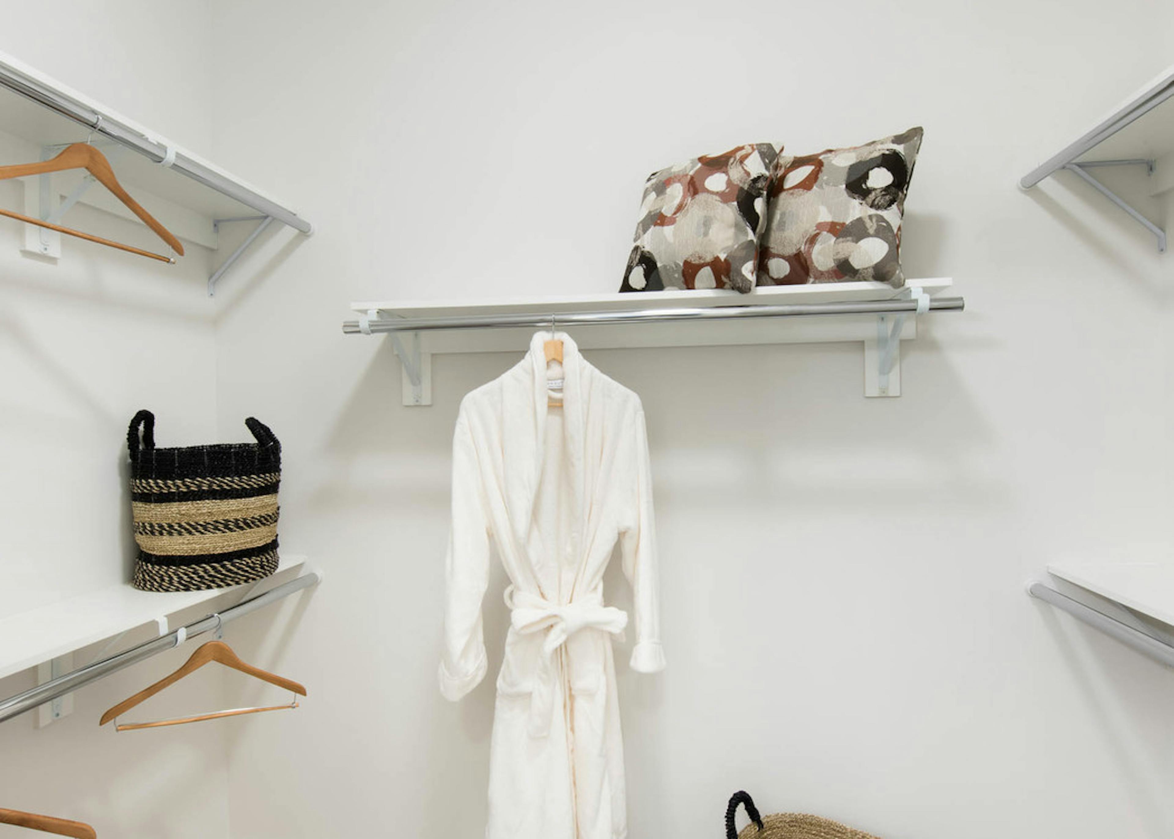 Interior view of a walk in closet at AMLI Buckhead with wooden hangers and white shelving with beige colored walls