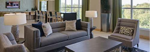 Clubroom at AMLI Evanston with grey couches and patterned lamps with large windows and barstool seating in the background