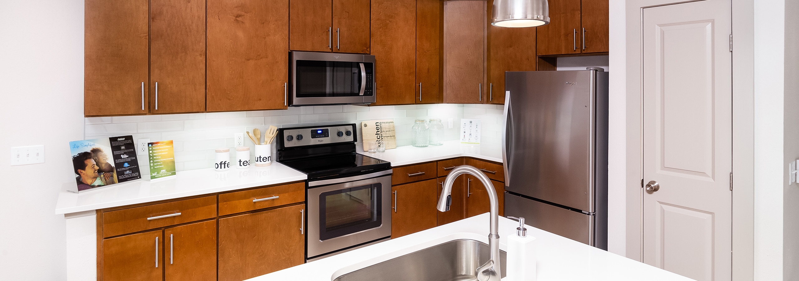 Interior view of a renovated kitchen island at AMLI Park Avenue apartments with white counter tops and many kitchen cabinets