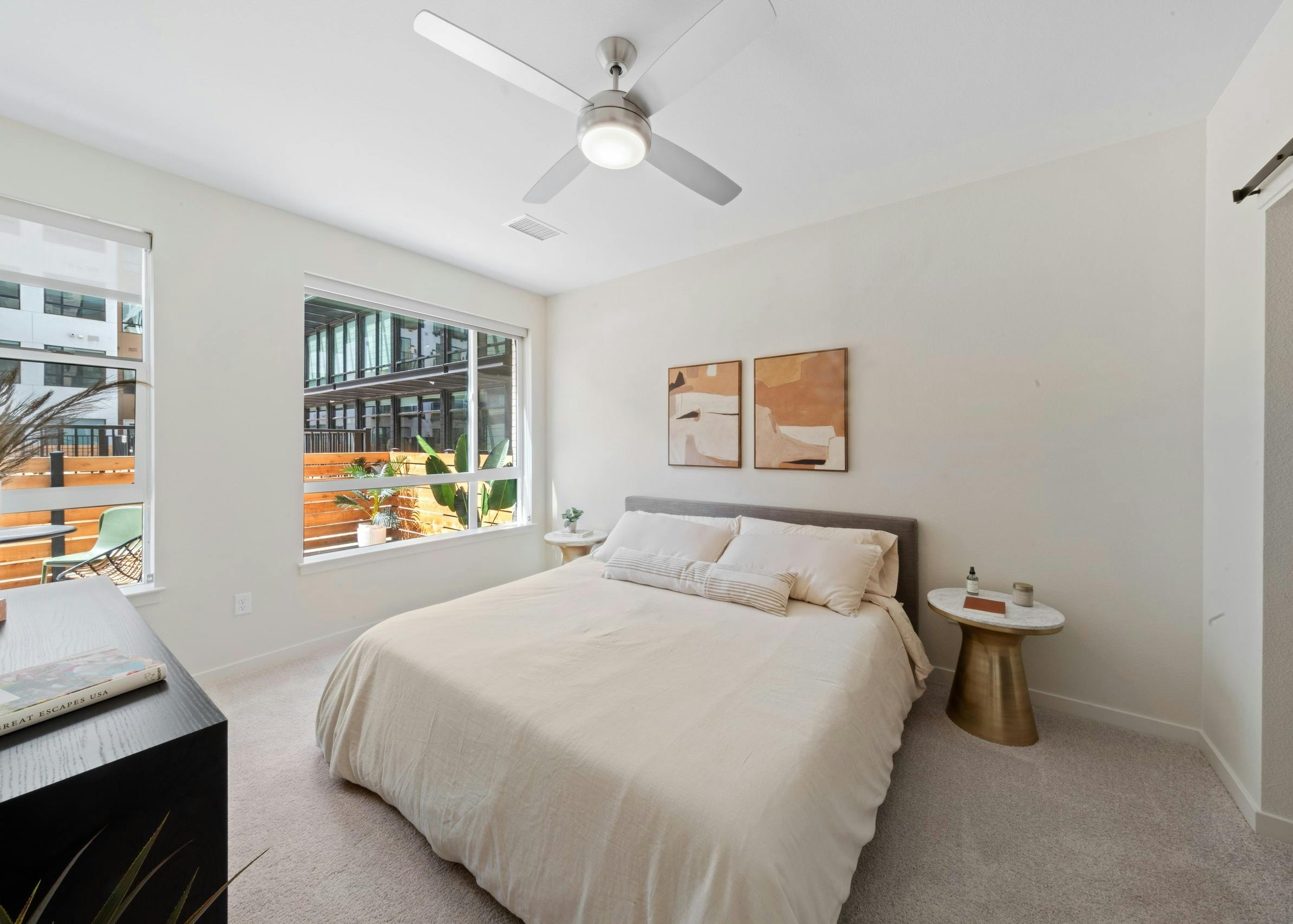 Bedroom at AMLI Broadway Park apartments with a queen size bed and a 2 large windows with a view out to the patio