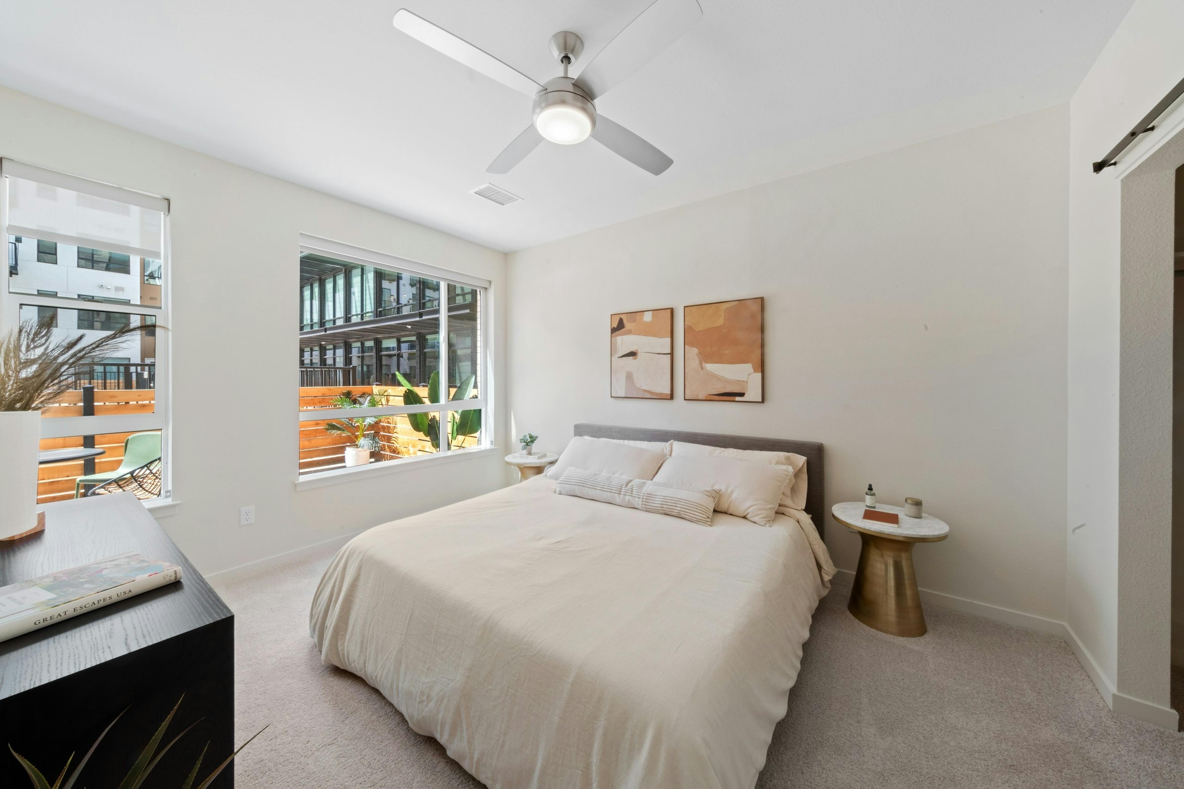 Bedroom at AMLI Broadway Park apartments with a queen size bed and a 2 large windows with a view out to the patio