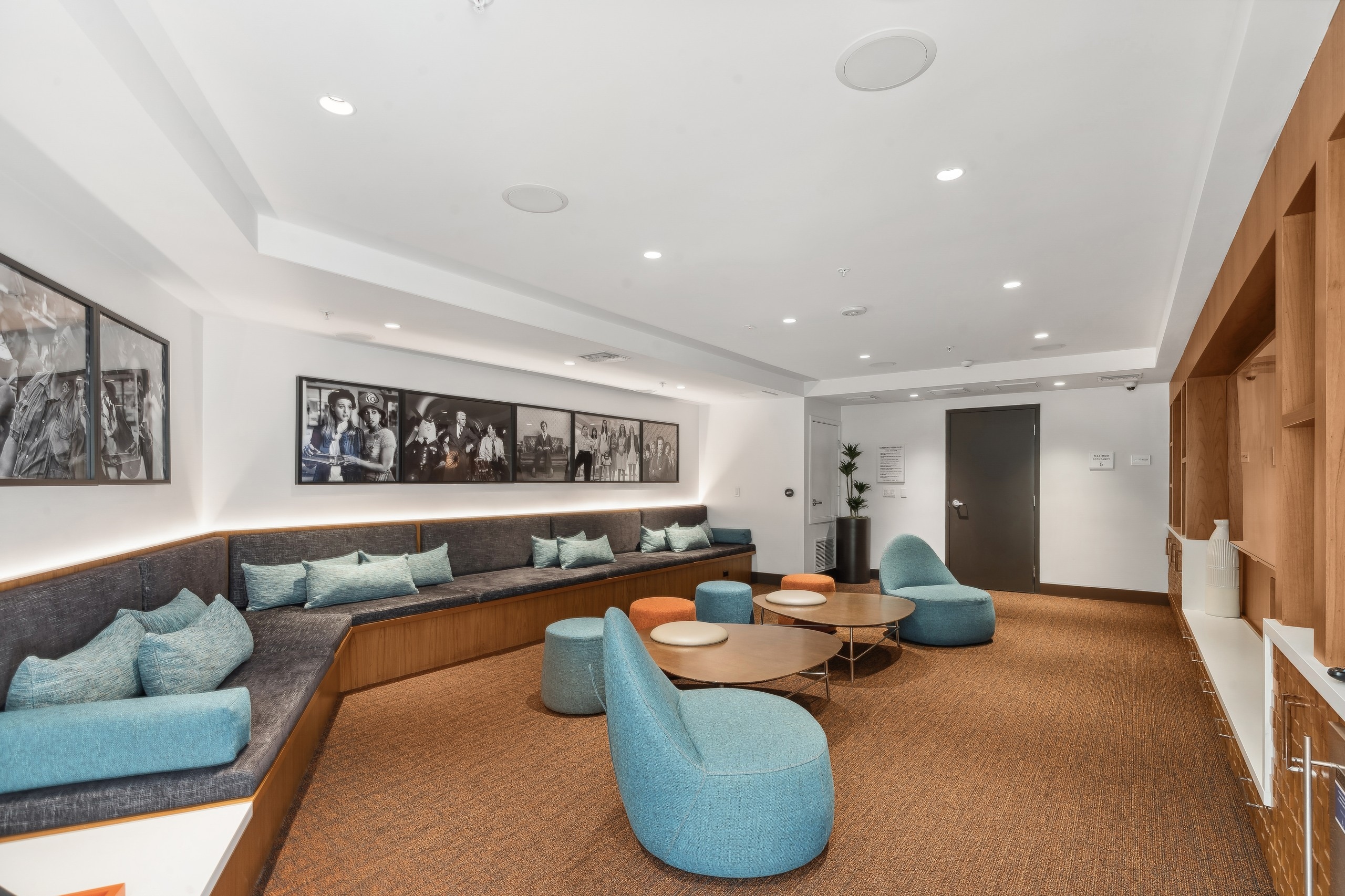 Media lounge with colorful lounge seating and tables and movie artwork on the walls at AMLI Uptown Orange

