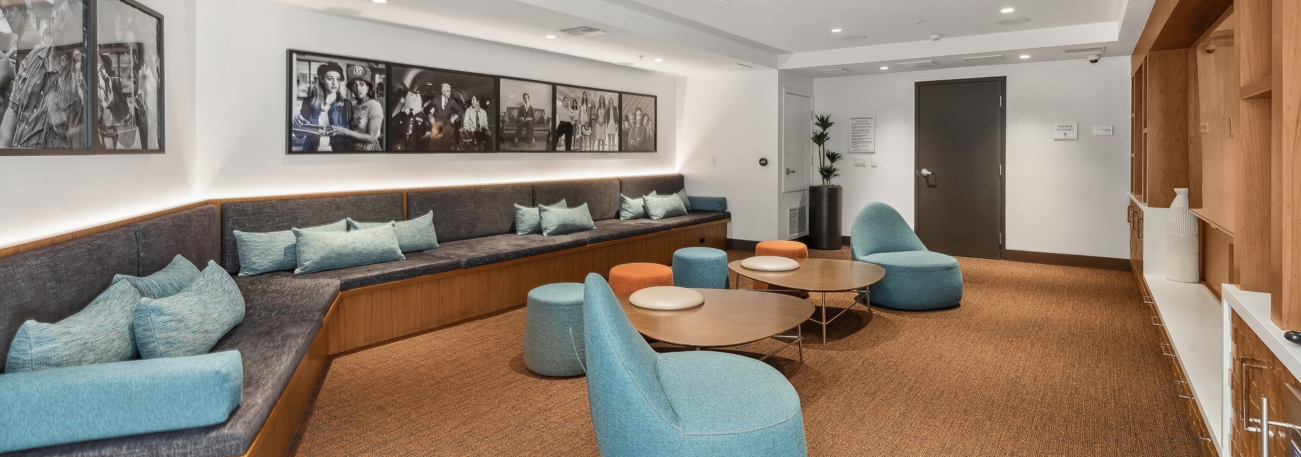 Media lounge with colorful lounge seating and tables and movie artwork on the walls at AMLI Uptown Orange