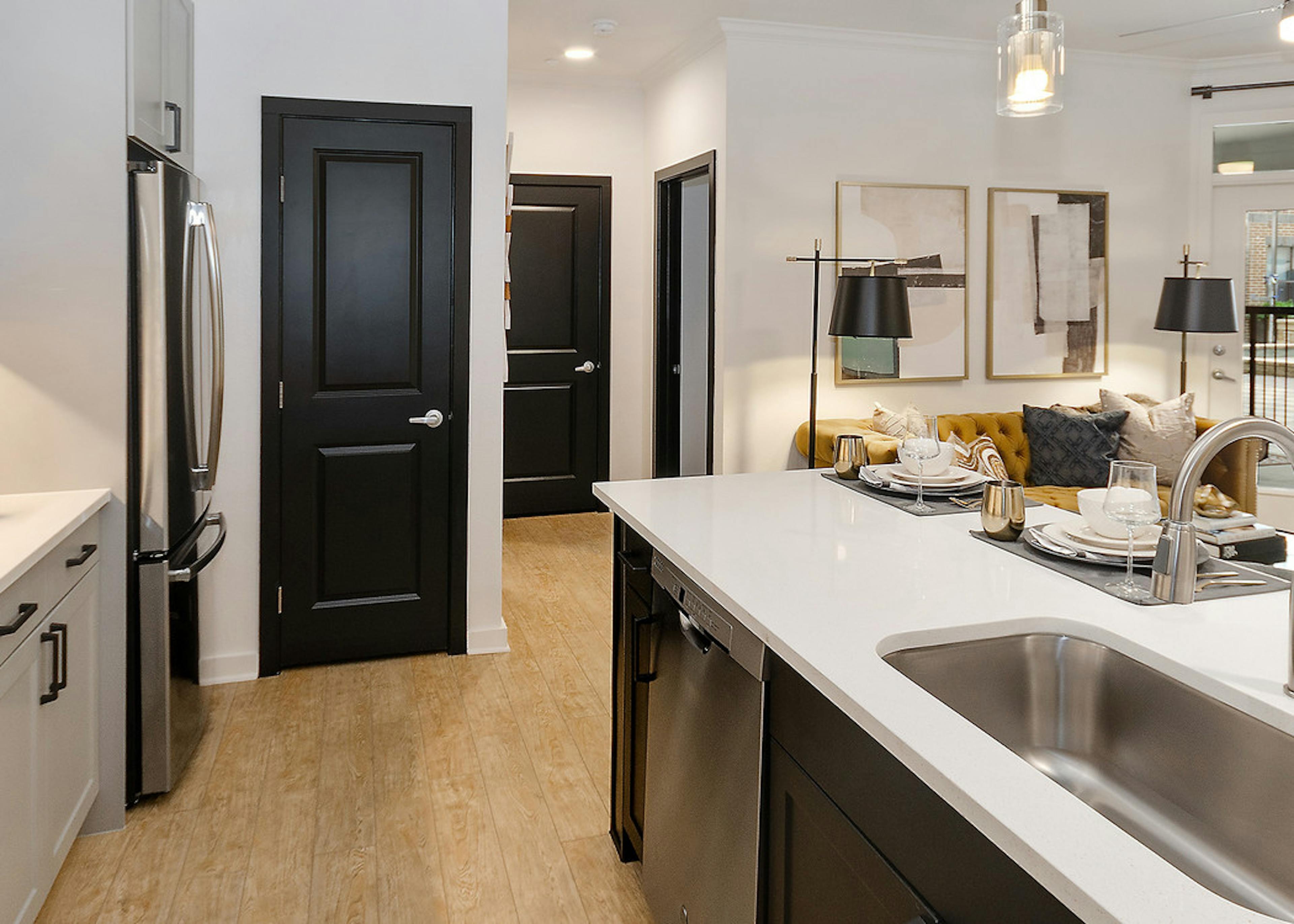 Kitchen at AMLI Quadrangle with white cabinets and countertops with stainless steel appliances and light wood flooring