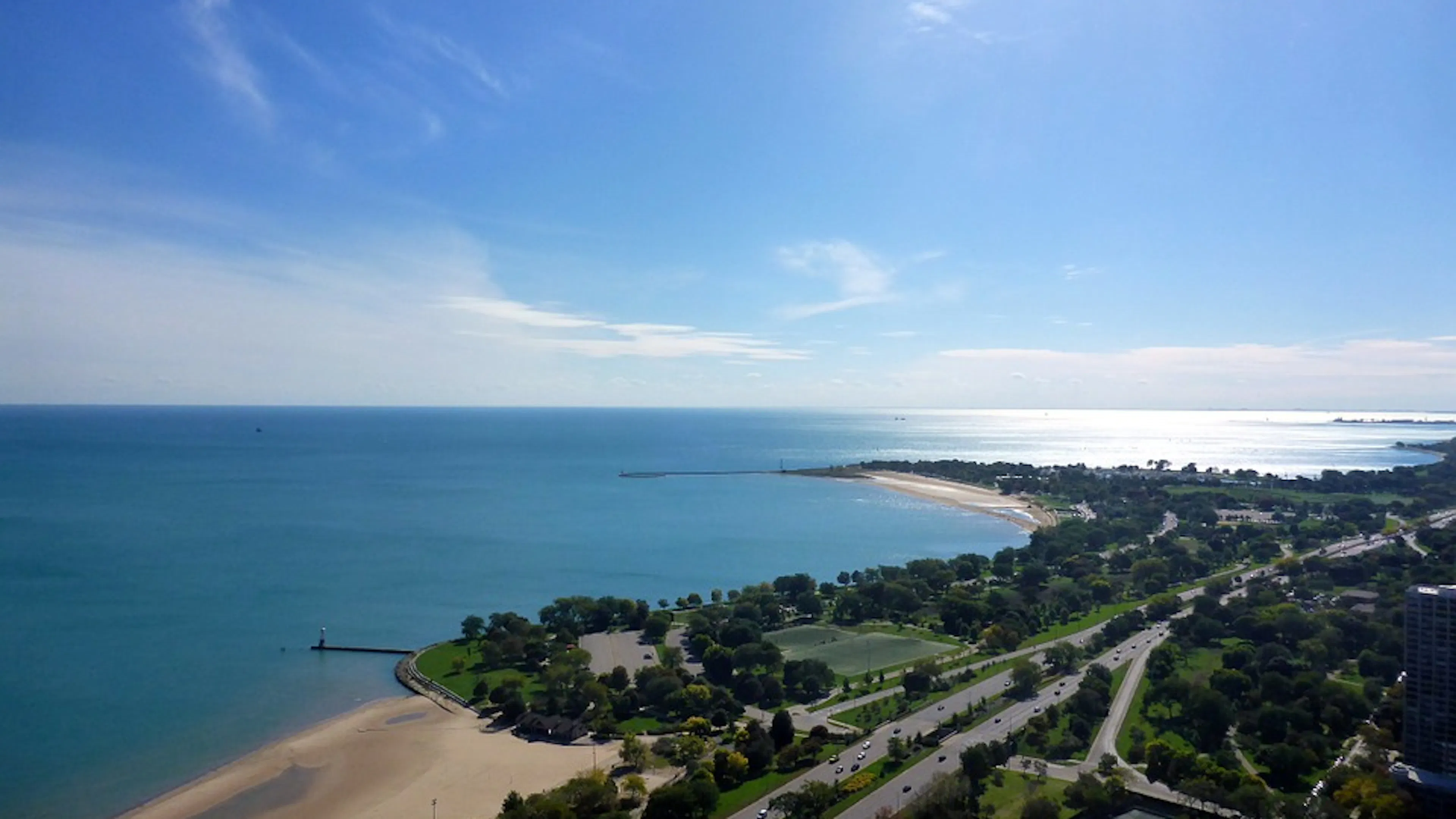 A wide view of the beachy shores of Lake Michigan on a clear blue sunny day