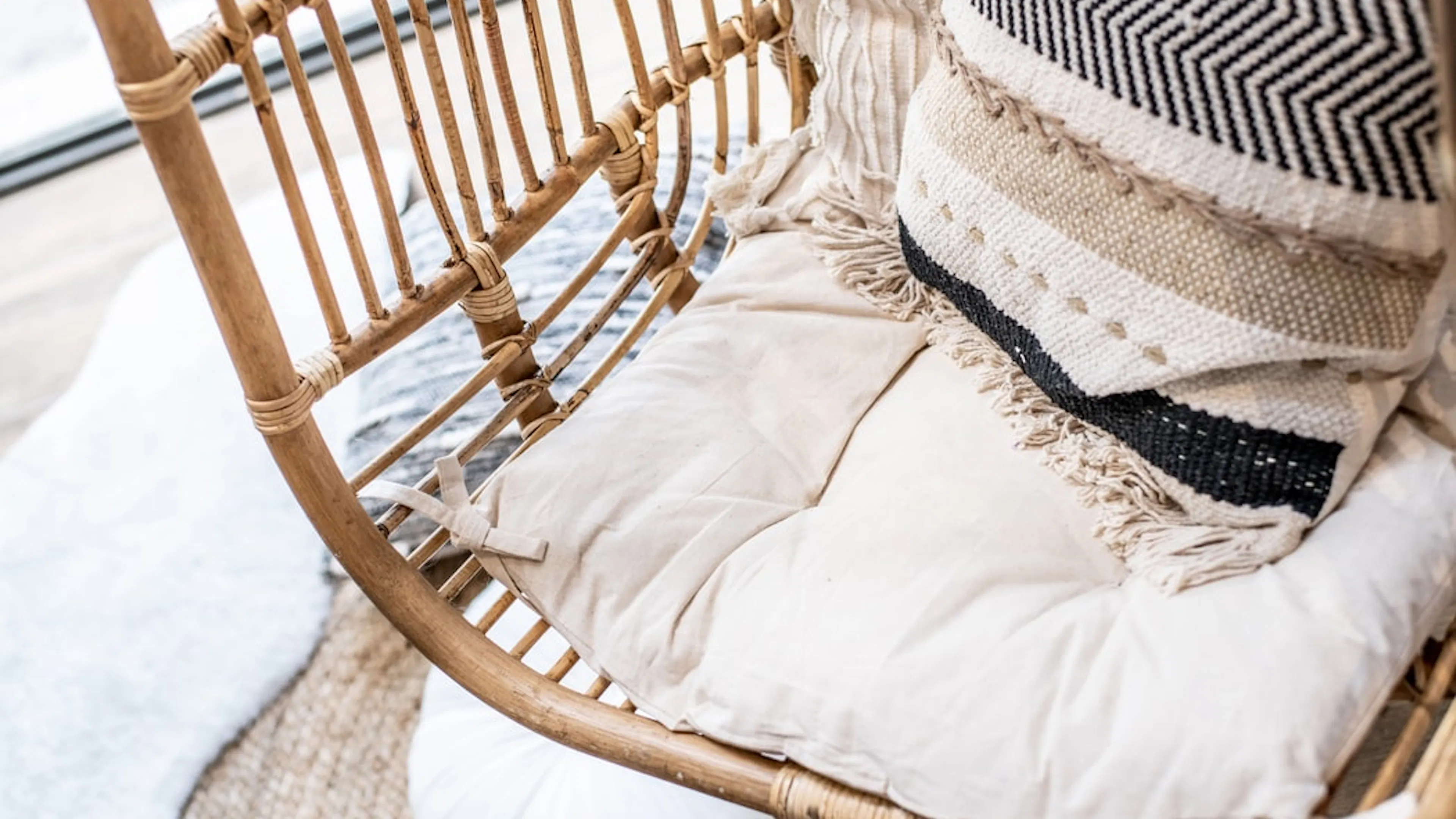 Close up of a wicker chair with a white pillow and a patterrned blue pillow