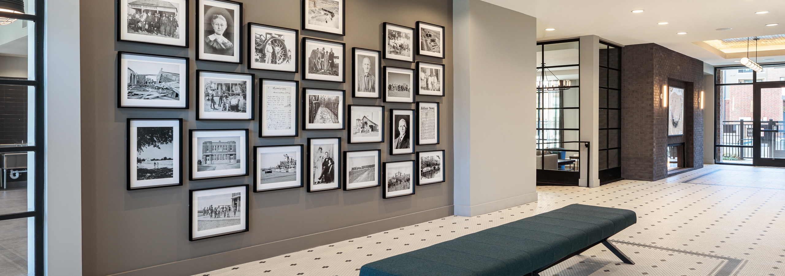 Close up of gallery at AMLI Addison with black and white photo frames of varying sizes hung on a dark wall with a long bench