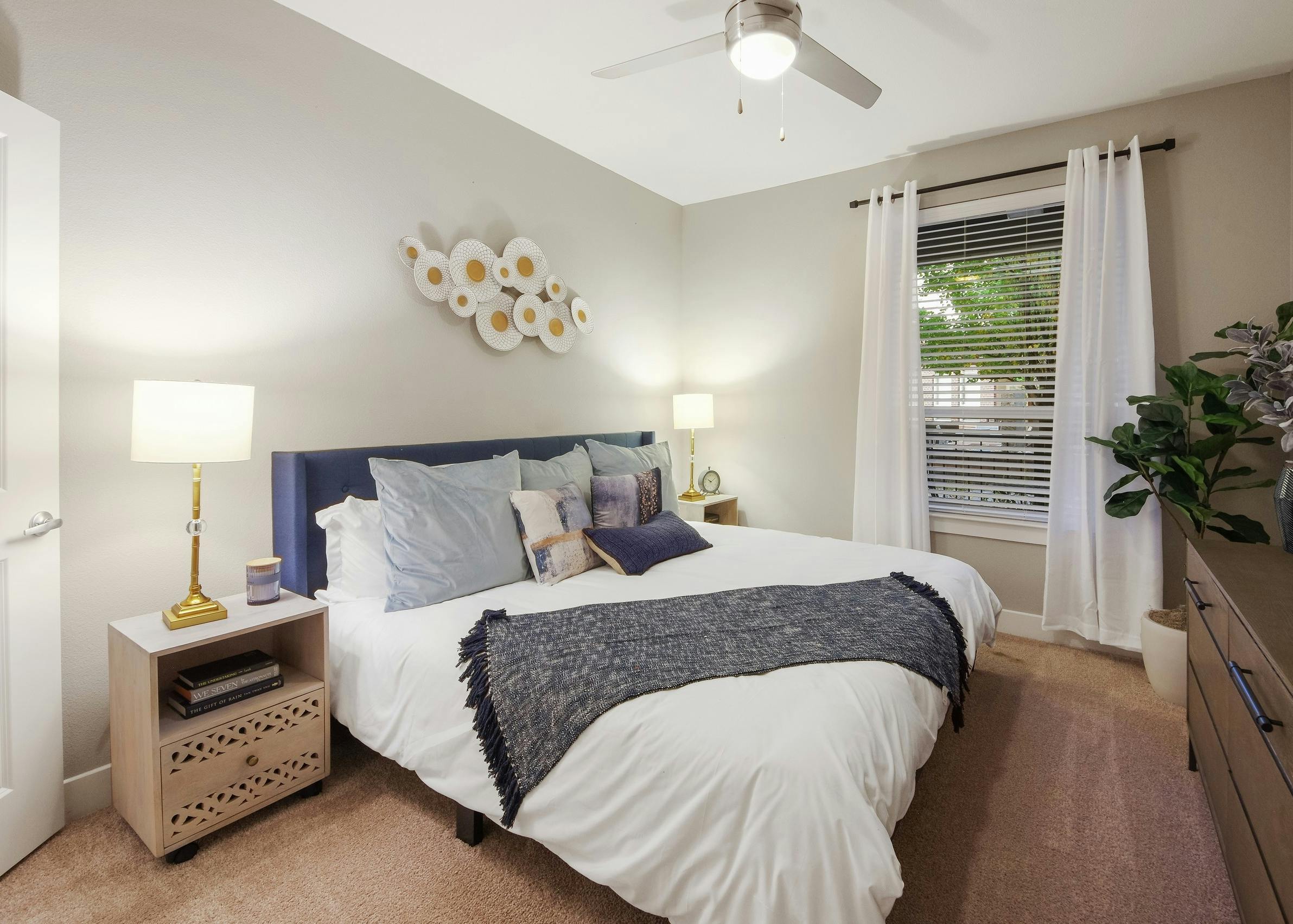 AMLI Riverfront Park apartment bedroom with light walls and carpeting featuring a spacious white bed with blue accents