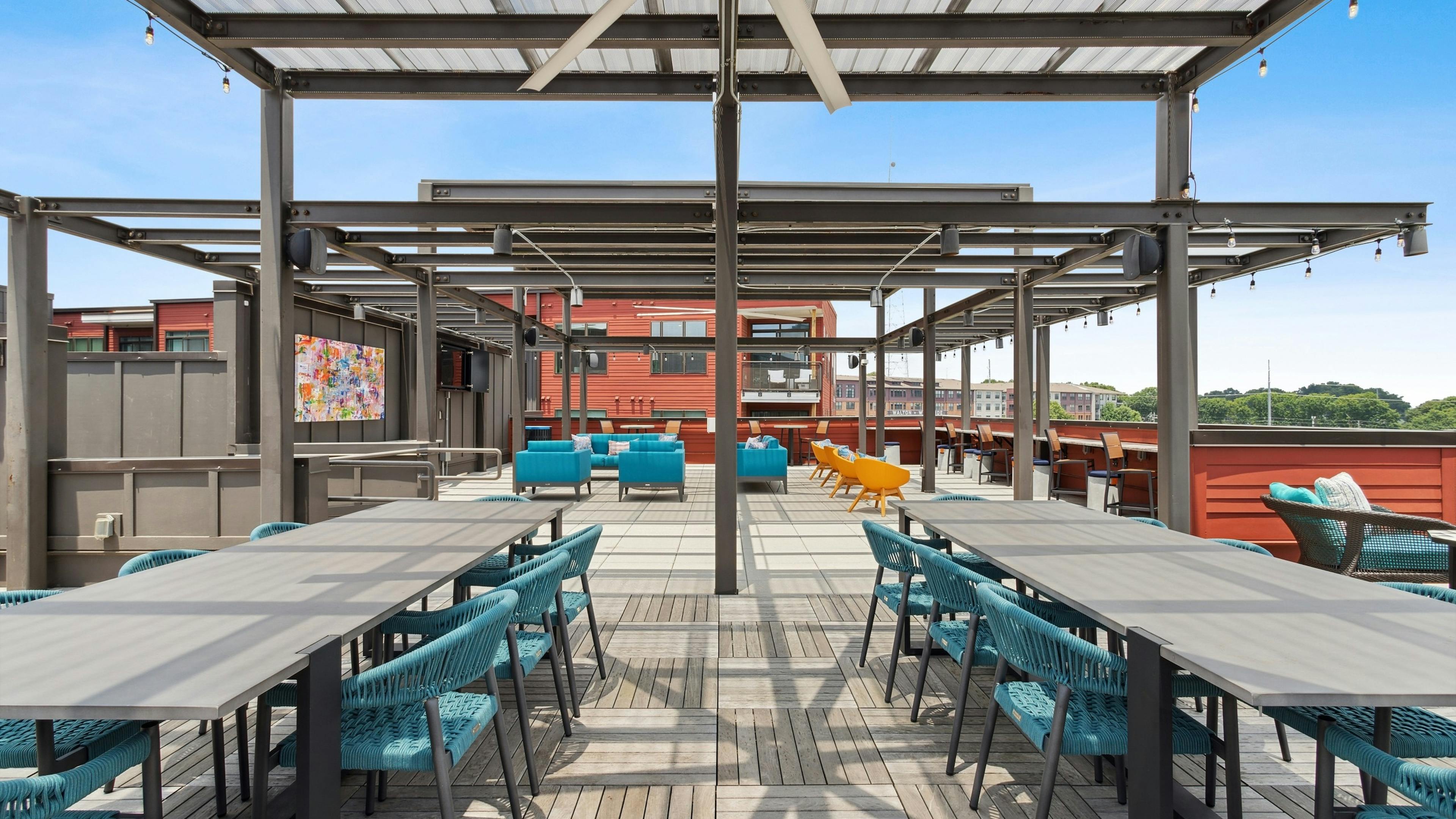 Exterior daytime view of expansive rooftop lounge at AMLI Westside with a variety of seating arrangements and flat screen TVs