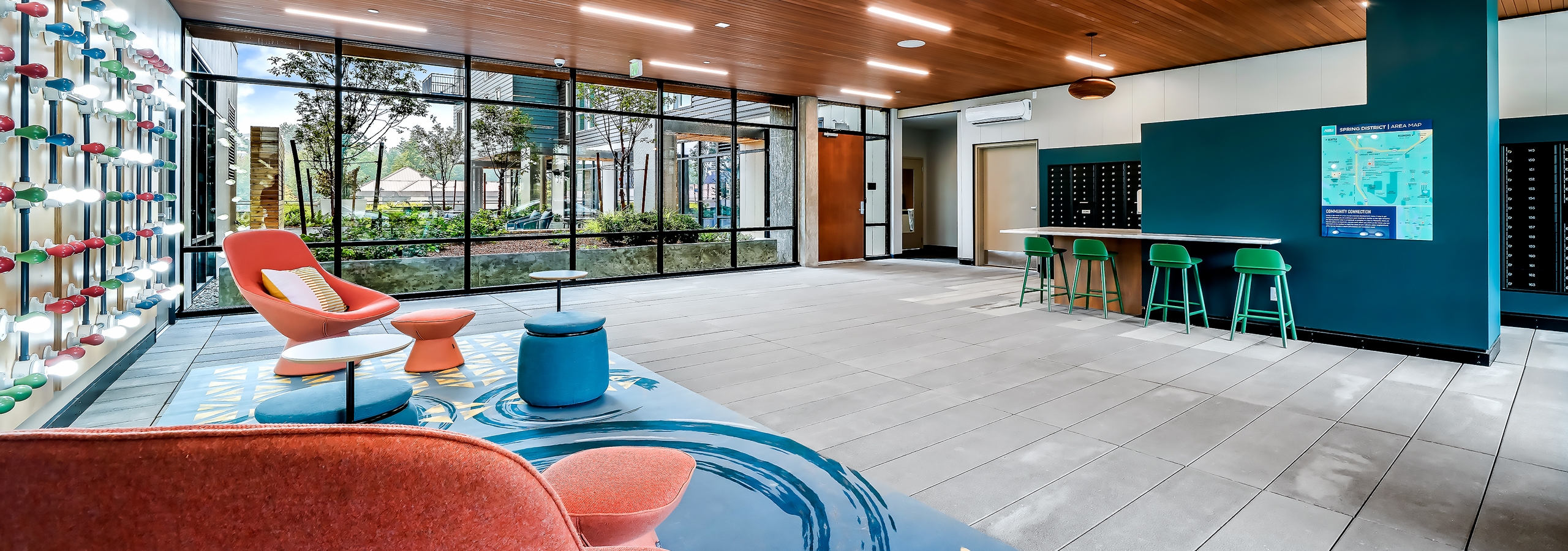 AMLI Spring District apartments mailroom with wall of windows and colorful seating areas and mailboxes along the back wall