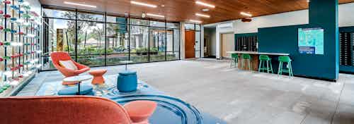 AMLI Spring District apartments mailroom with wall of windows and colorful seating areas and mailboxes along the back wall