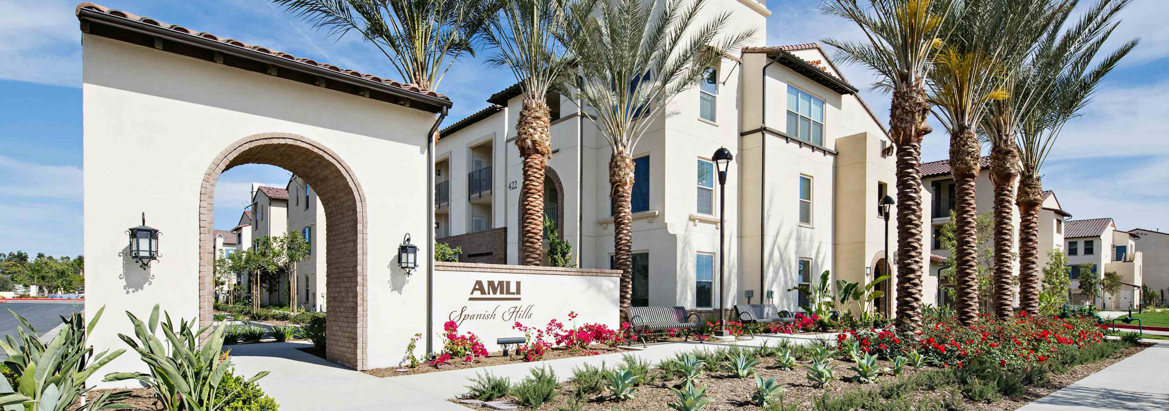 Daytime view of landscaped rendering of AMLI Spanish Hills apartment building’s Spanish colonial architectural façade 