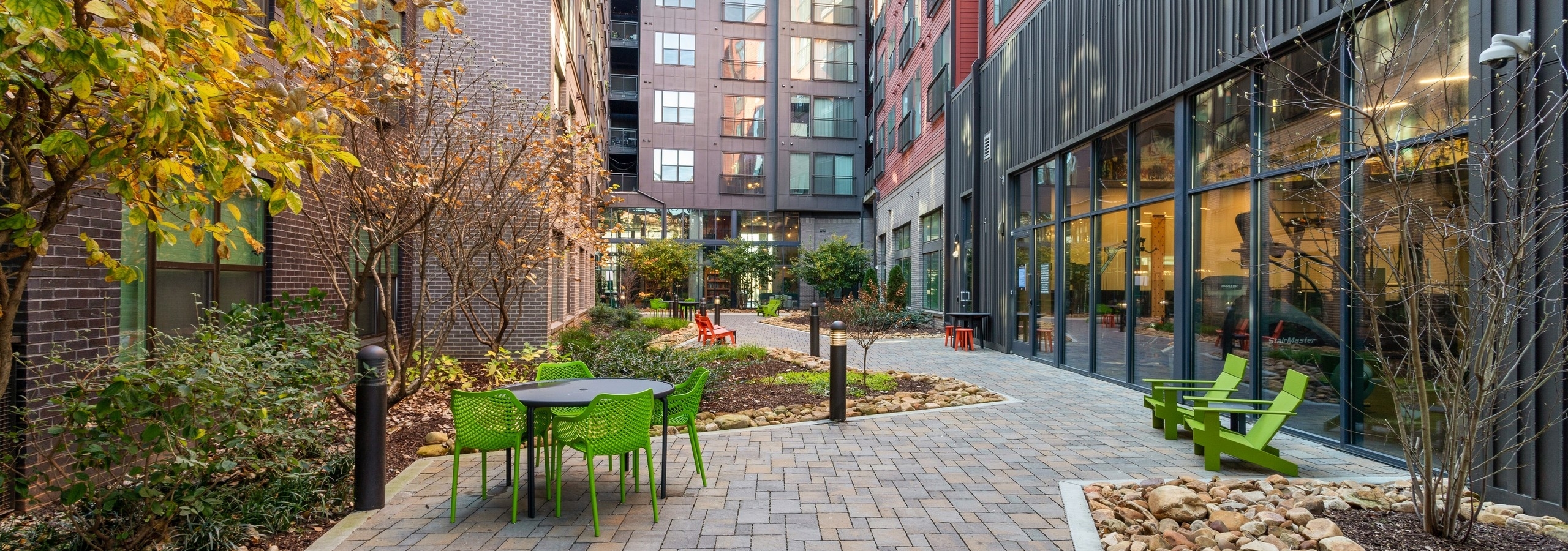 Landscaped courtyard at AMLI Westside apartments with brick walkway and various seating areas and peek into fitness center