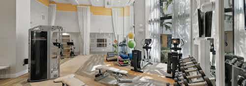 Interior of the fitness center at AMLI 8800 with treadmills, weight machines, yoga balls and vibrant yellow walls