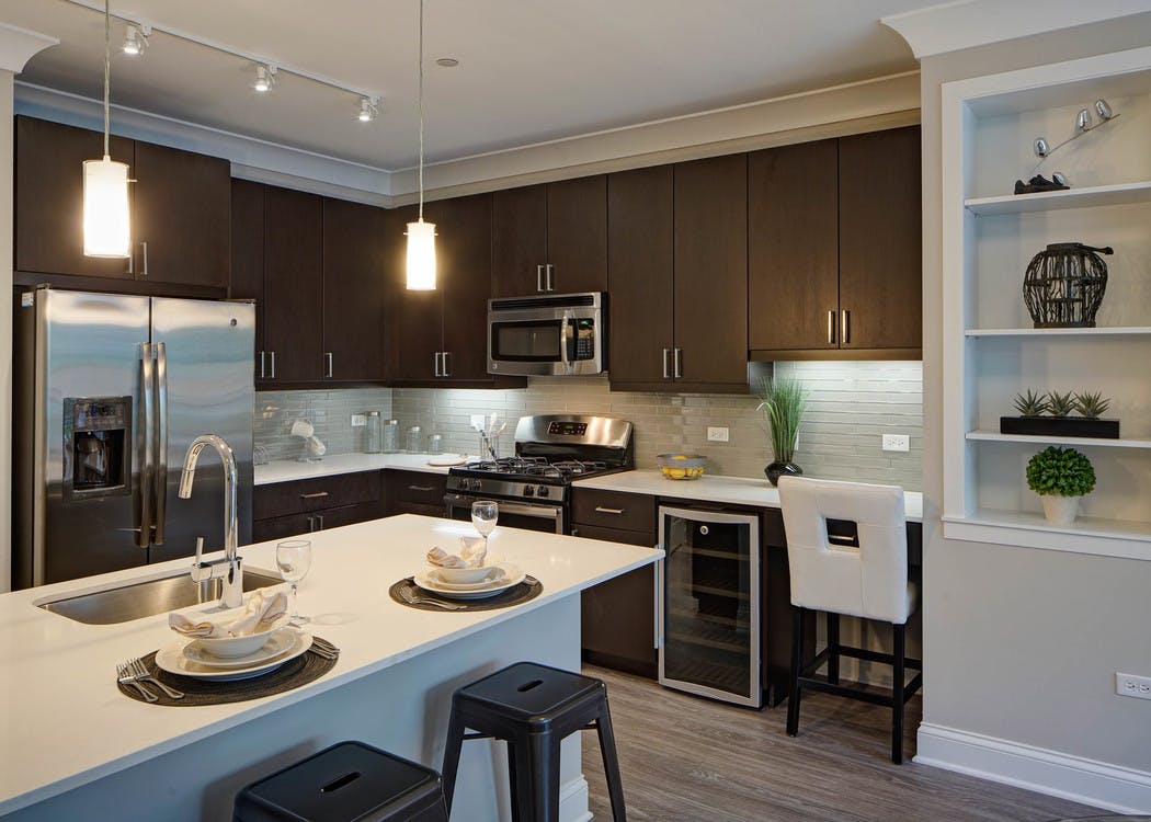 Interior of AMLI Deerfield kitchen with dark wood cabinets and stainless steel appliances with quartz countertop and island