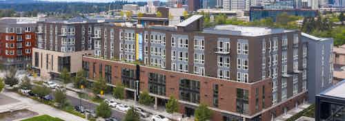 Aerial view of AMLI Spring District apartment building with rooftop deck above and street with cars and skyline in rear
