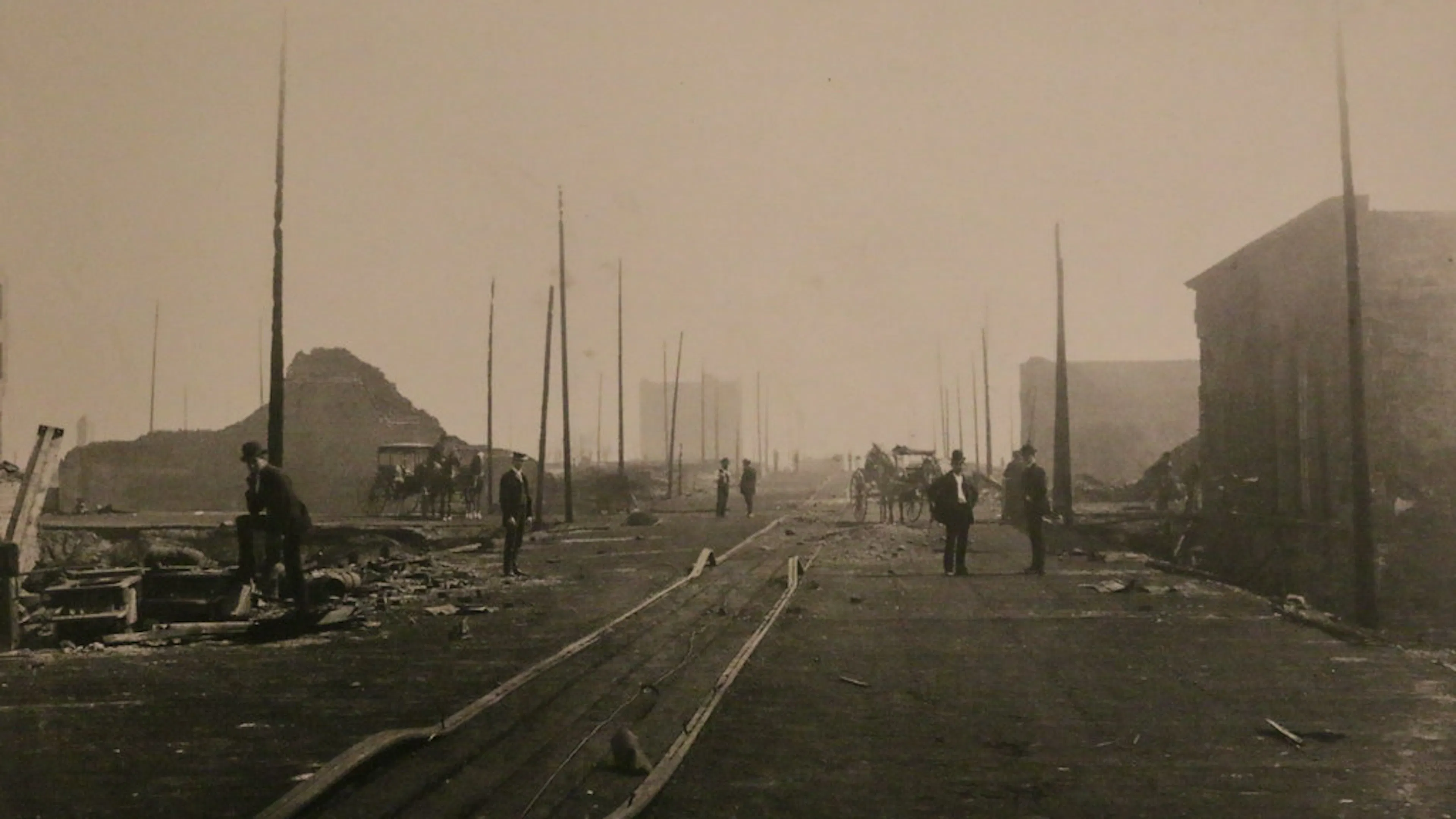 an empty road flanked by burnt-down buildings in Seattle circa 1889