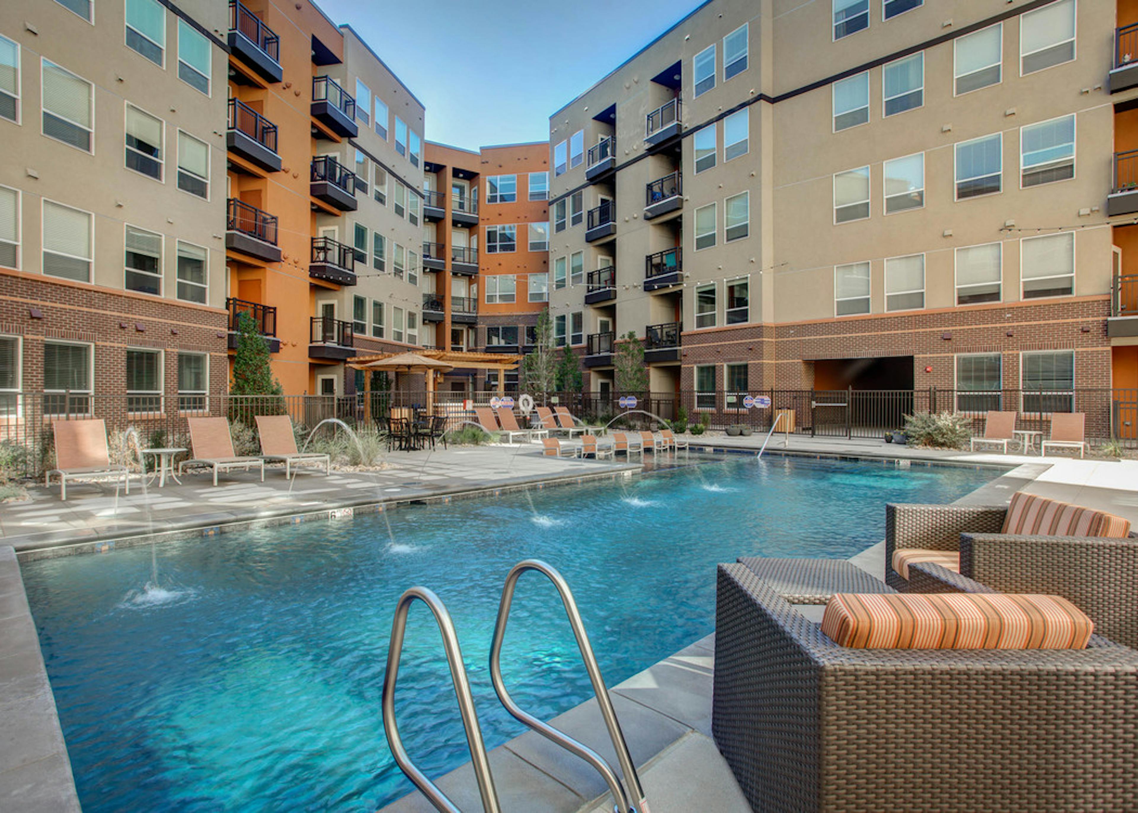 Exterior view of the pool at AMLI Riverfront Park apartments with padded lounge chairs and a view of the apartment building 