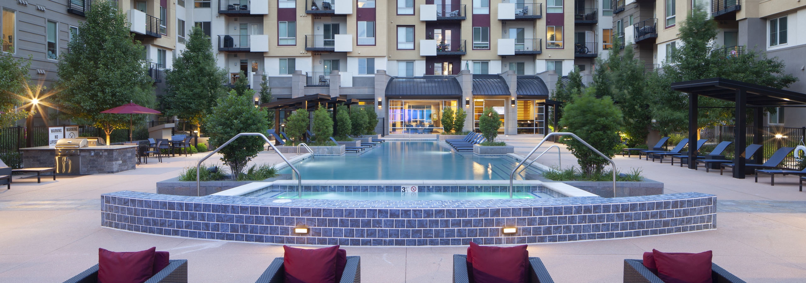 Exterior view of the pool at AMLI Cherry Creek apartments with a fire pit and grilling areas and multiple seating areas
