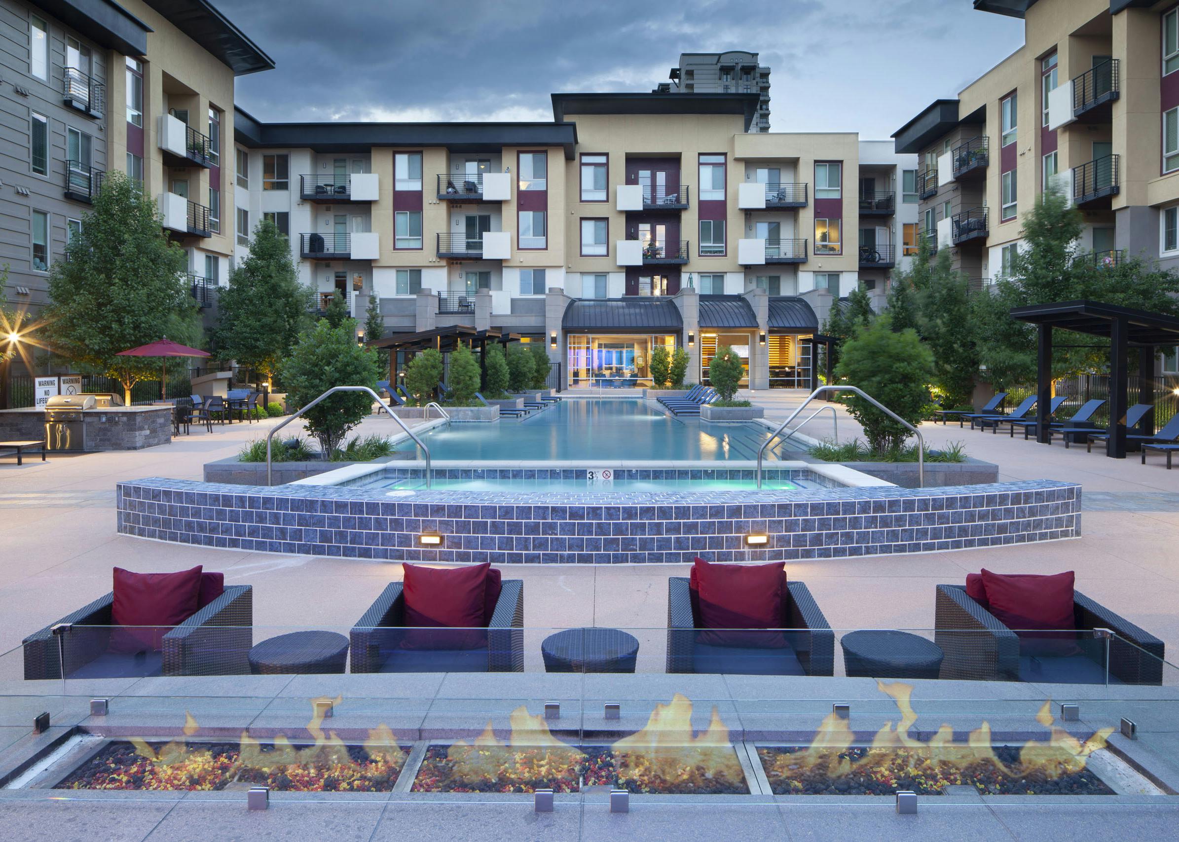 Exterior view of the pool at AMLI Cherry Creek apartments with a fire pit and grilling areas and multiple seating areas