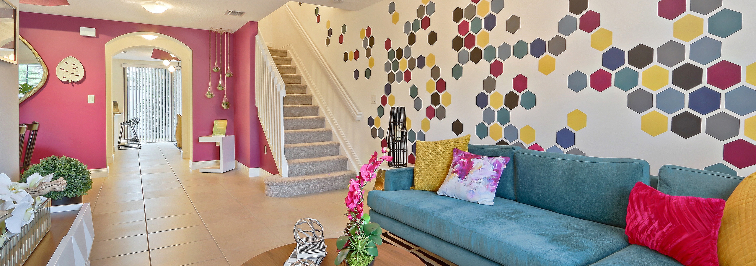 AMLI Toscana Place townhome apartment living room with colorful wall mural and vibrant decor, sofa and peek up the staircase