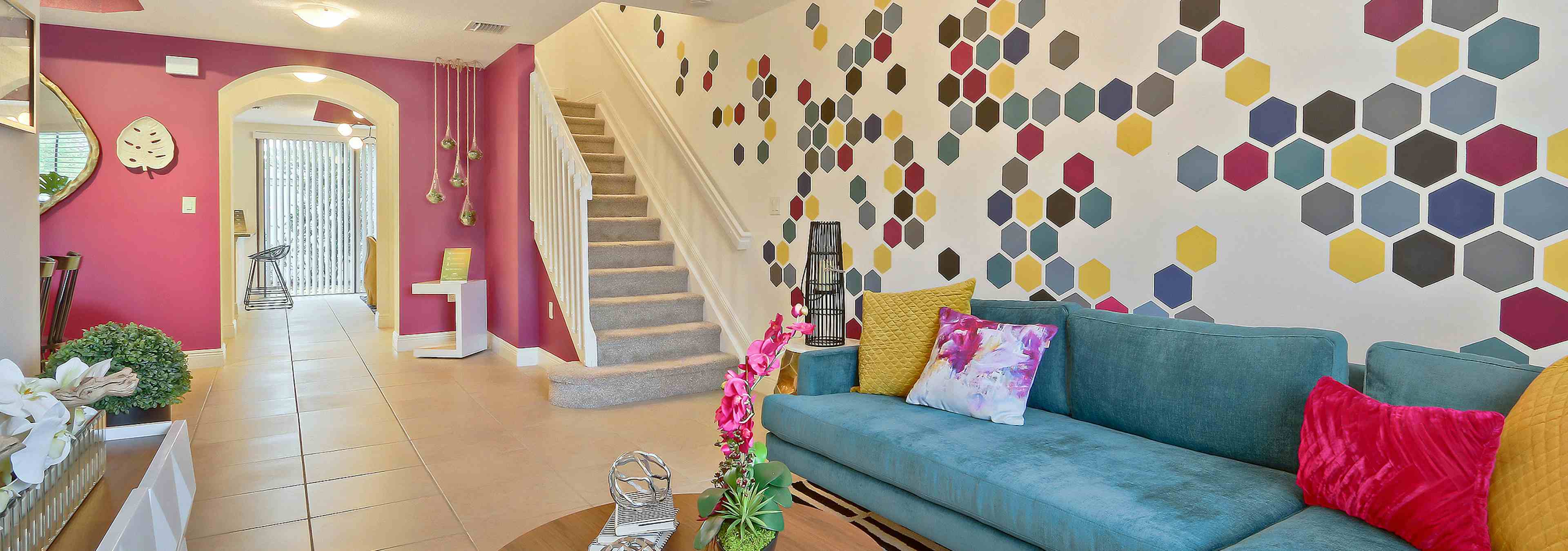 AMLI Toscana Place townhome apartment living room with colorful wall mural and vibrant decor, sofa and peek up the staircase