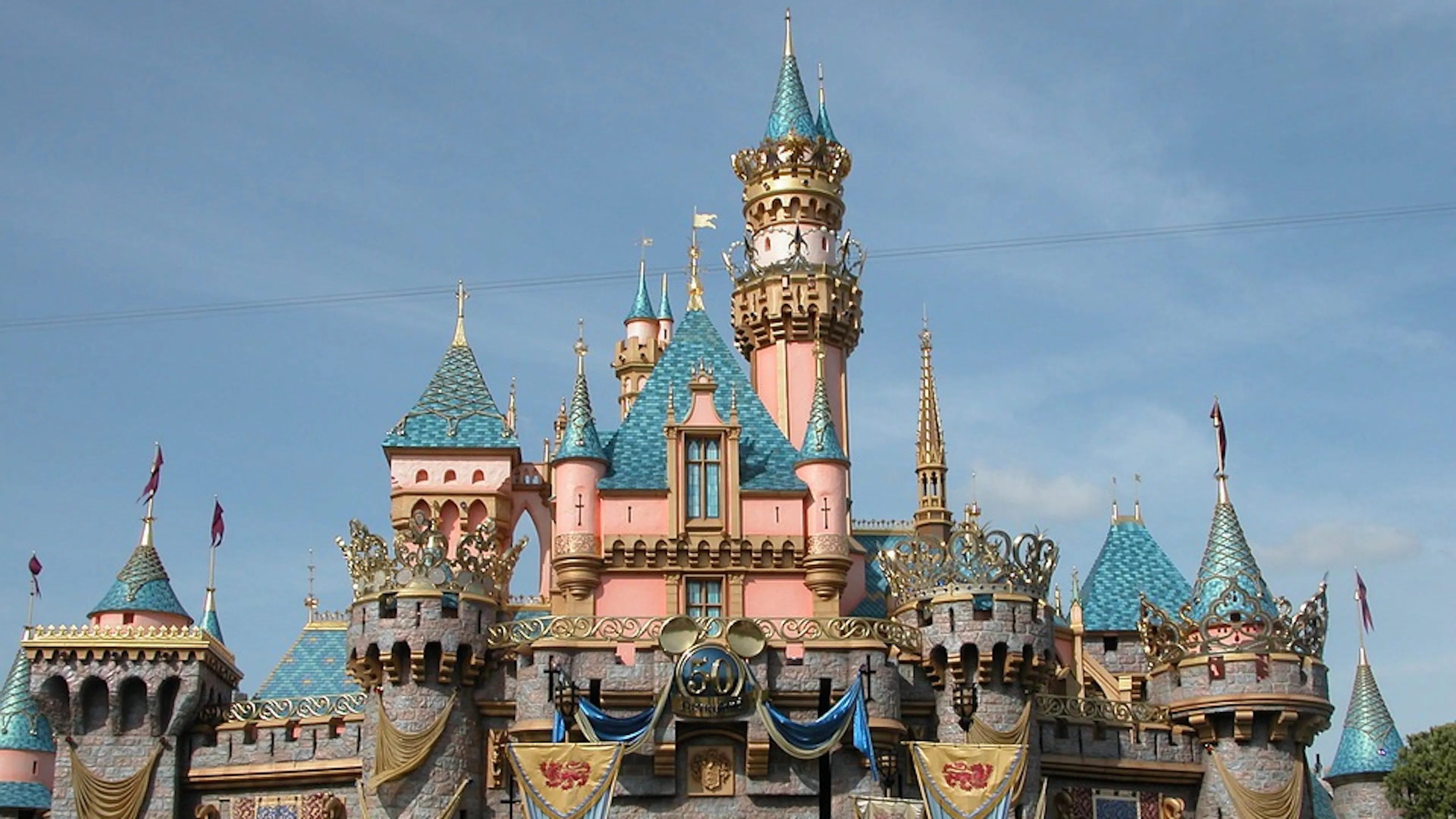 A wide angle shot of the Disneyland castle set against a clear blue sky