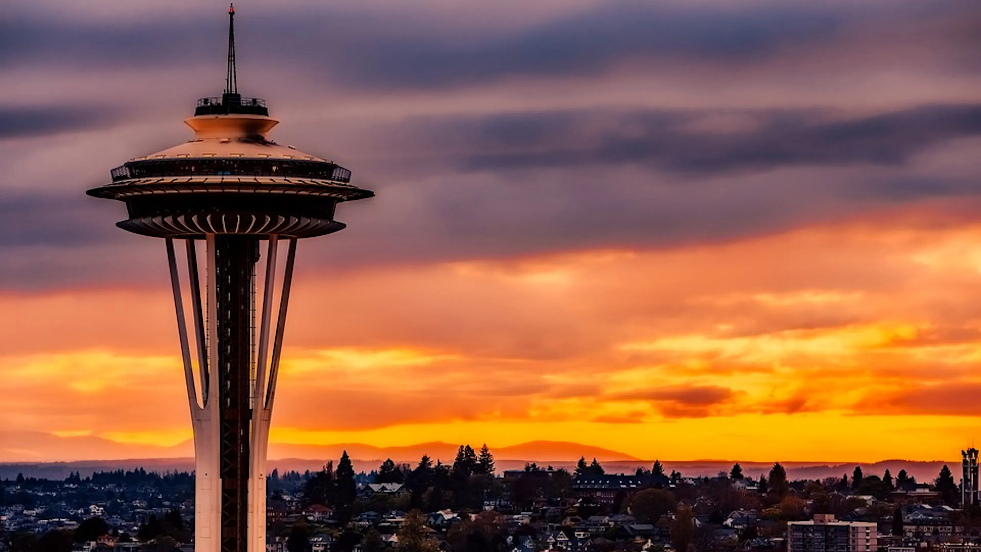 The Seattle Space Needle set against a bright orange sunset