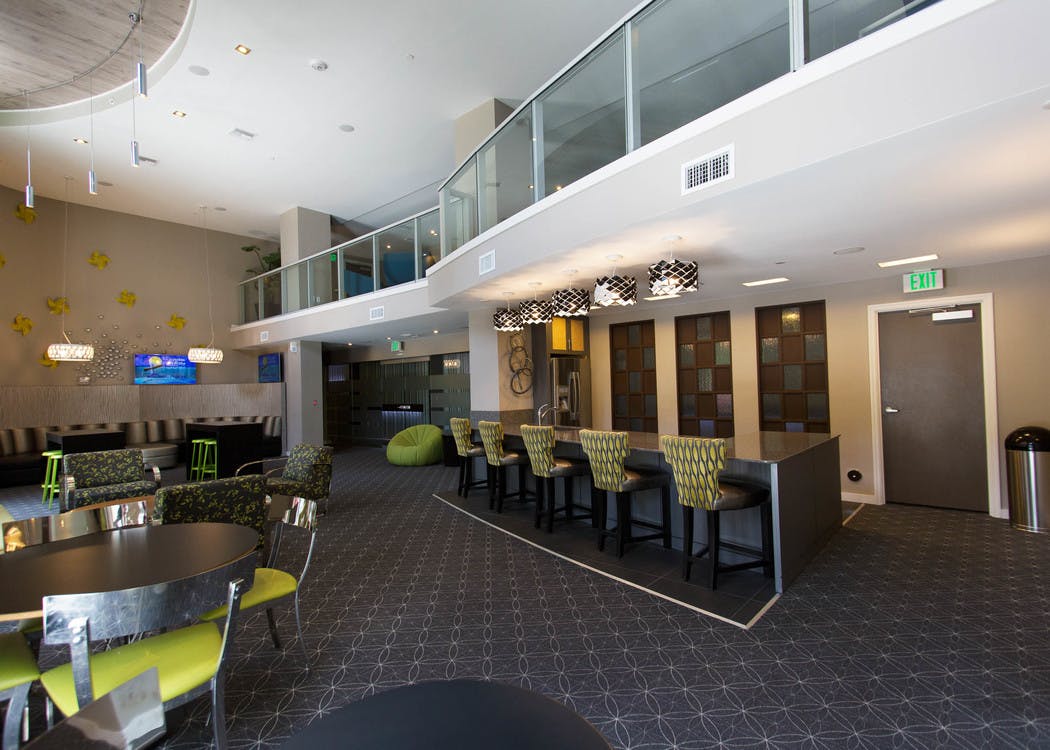 Two story resident lounge at AMLI Dadeland with bright green accent furniture and fully equipped kitchen with bar stools