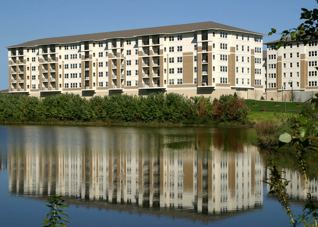 Exterior view of the lakeside AMLI at Seven Bridges apartment community building with a brown and ivory brick facade