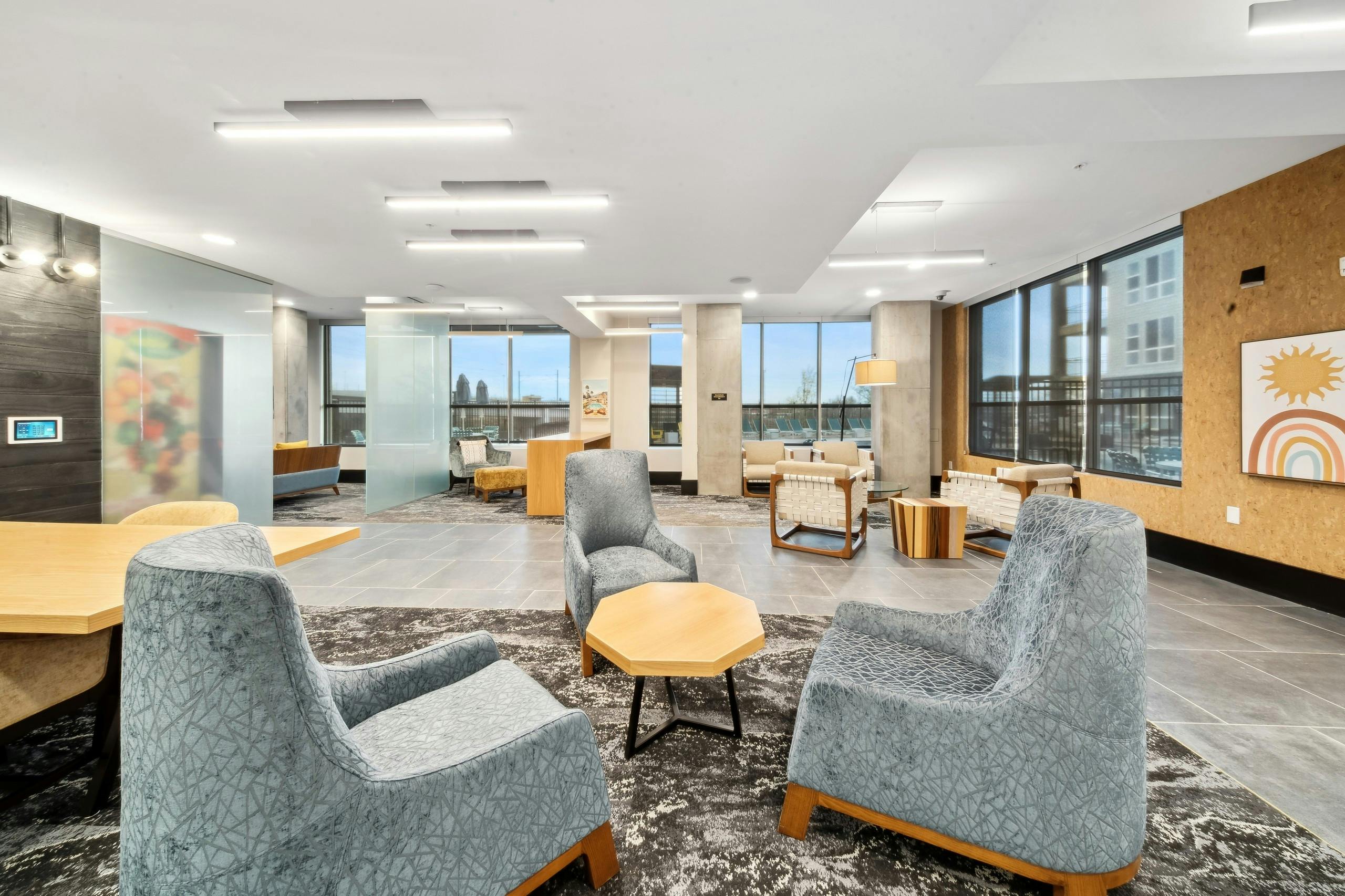 Business center at AMLI RiNo with 3 blue velvet chairs and other seating and tables with a view of pool and skyline